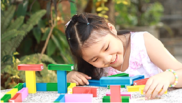 A Smiling girl enjoying with building blocks