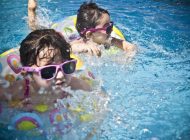 Two adorable kids playing and swimming in a pool