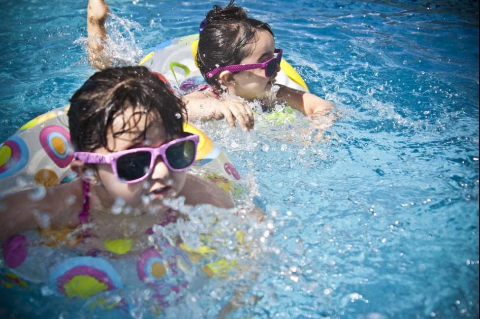 Two adorable kids playing and swimming in a pool