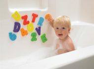 A kid playing with alphabets while bathing