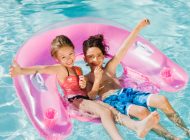 Two little girls relaxing on an inflatable toy ring floating in a pool