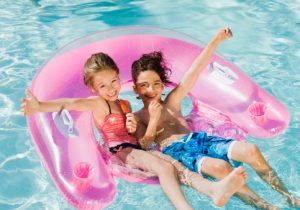 Two little girls relaxing on an inflatable toy ring floating in a pool