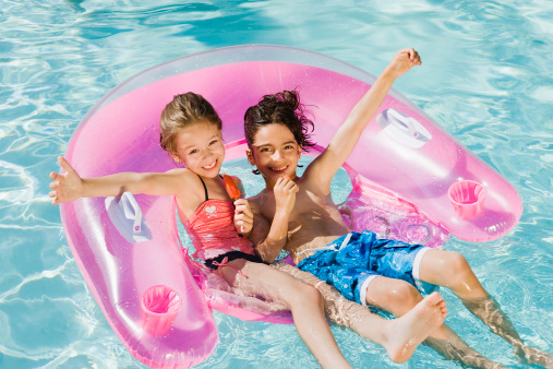 Two little girls relaxing on an inflatable toy ring floating in a pool