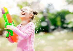 Smiling girl playing and enjoying with water bubble gun