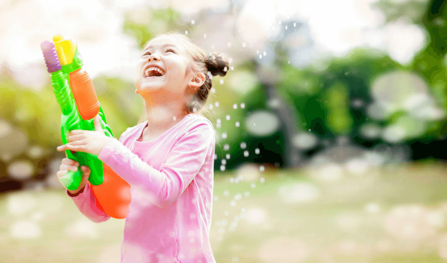 Smiling girl playing and enjoying with water bubble gun