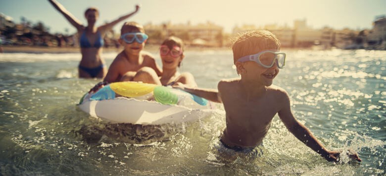 An Image of group of smiling kids enjoying in a pool on a sunny day