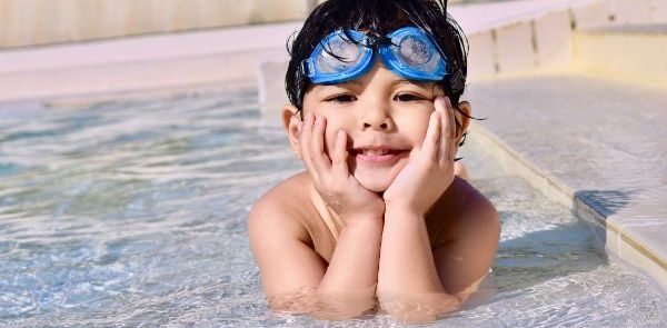 A Small kid giving cute pose from the pool with goggles